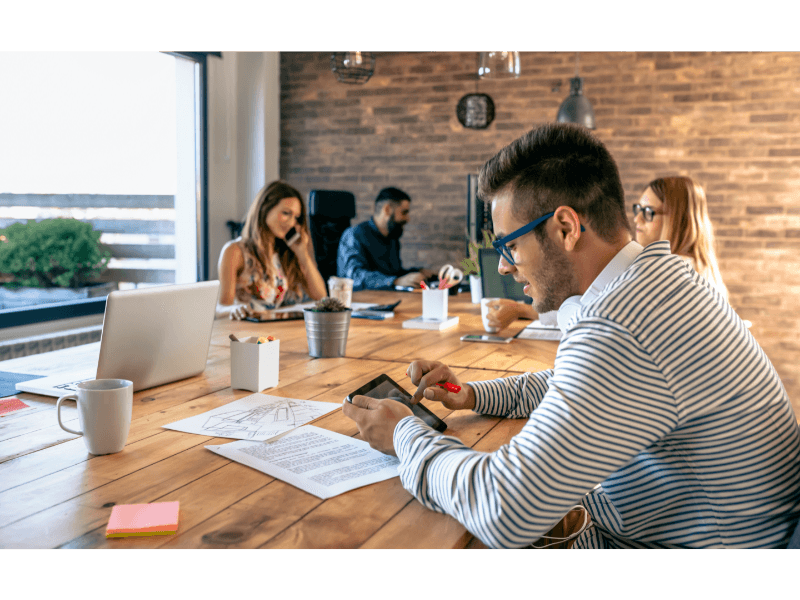 Vad innebär coworking? En djupdykning i den moderna arbetsmiljön En grupp av yrkesverksamma arbetar tillsammans i ett öppet och inspirerande coworking-utrymme